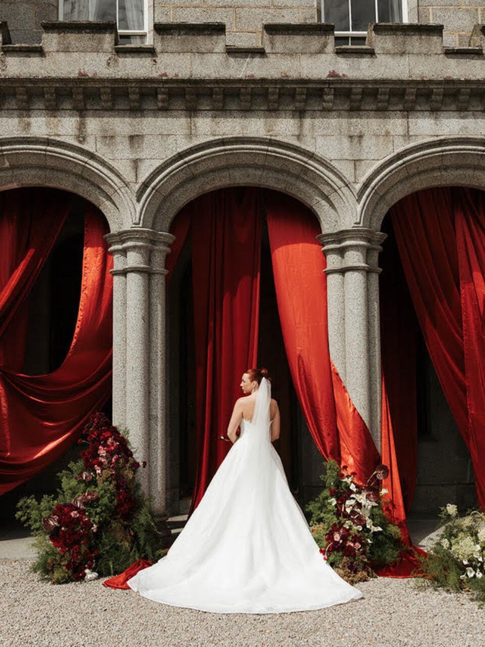 Bride outside building with red drapes in background